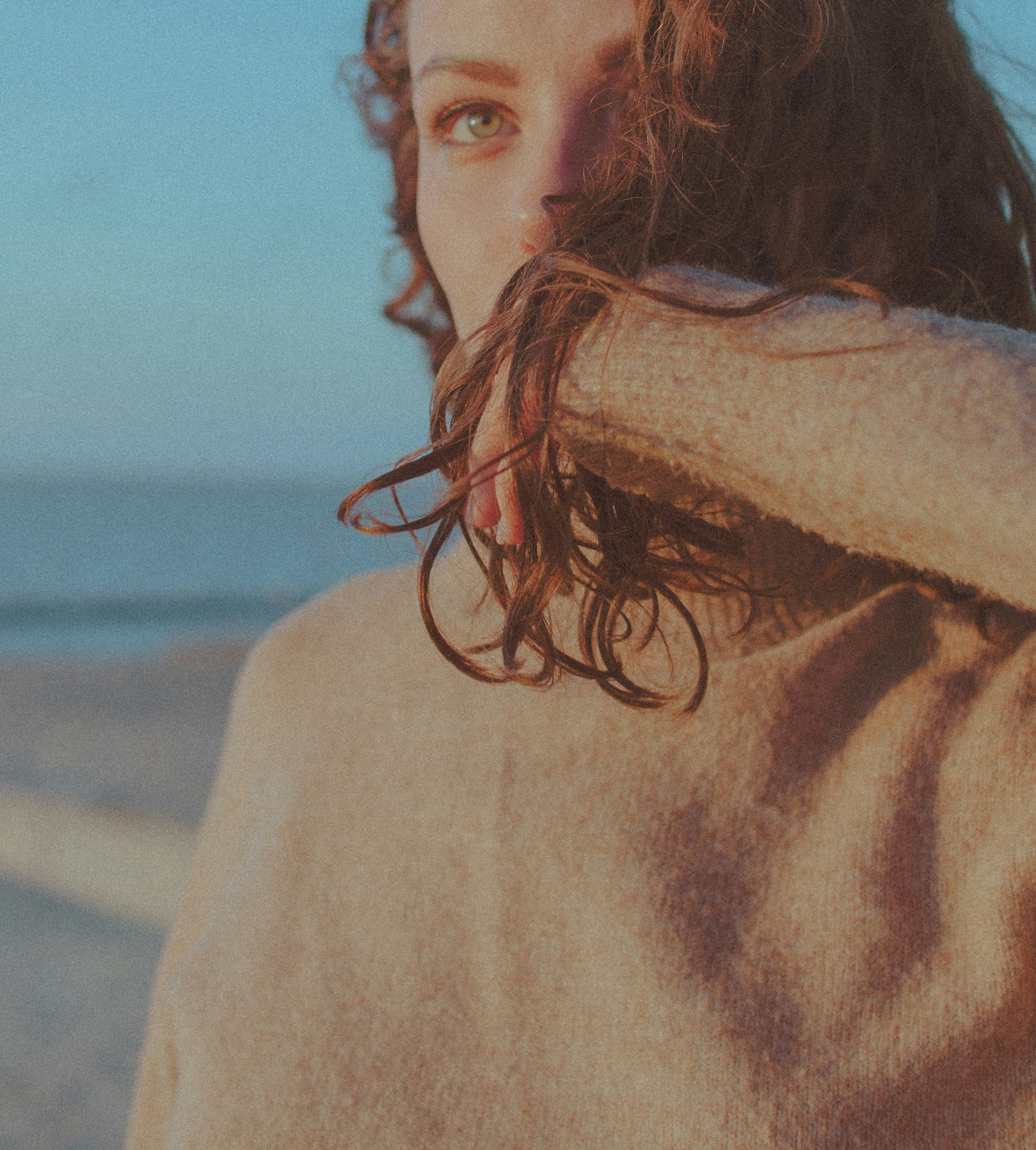 woman in white sweater standing on beach during daytime